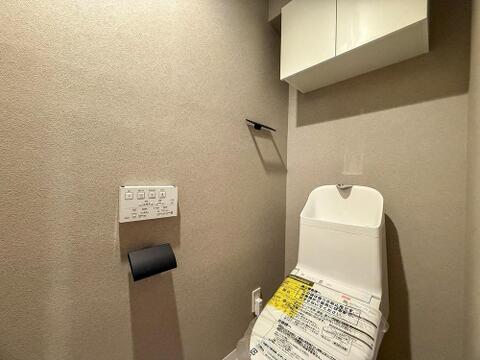 清潔感あふれるトイレは、ウォシュレット機能付きで家族みんなが快適です。上部の収納棚でストック品もすっきり片付き、いつも気持ちの良い空間を保てます。