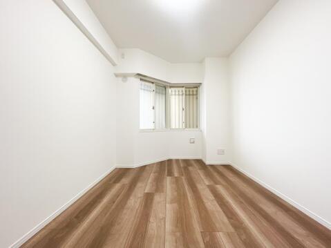 明るい自然光が広がる、変形窓のデザインが個性的な洋室。白を基調とした壁面と温かみのあるフローリングが、健やかな空間を演出します。おもちゃや学習机も配置しやすく、お子様のお部屋にぴったりです。
