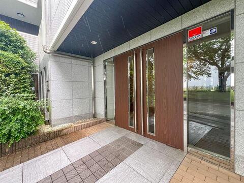 マンションの顔となるエントランスは、緑の植栽に映えるモダンな木目調デザイン。