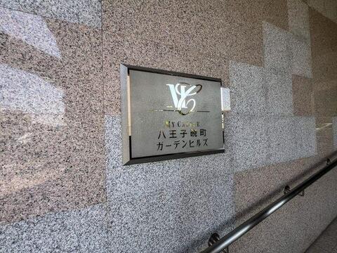 「MY CASTLE 八王子暁町 ガーデンヒルズ」の看板が迎えるエントランス。上質な石材の壁が、ご家族の帰りを優しく包み込みます。
