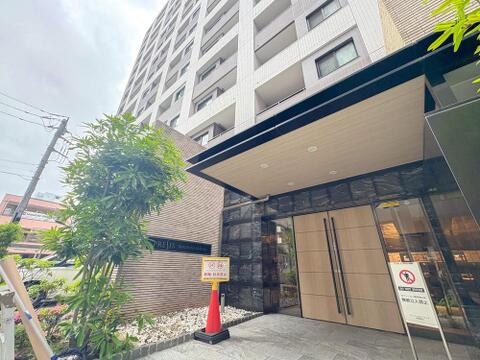 「PRESIS HACHIOJI REGLIO」の洗練されたエントランス。木目調のドアと重厚な石材が、家族の帰りを温かく迎えます。上質な空間が、日々の暮らしに彩りを添えます。