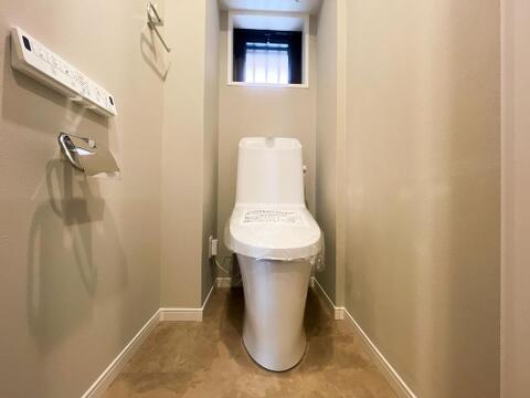 心地よい自然光を採り込み、爽やかな風が通る換気窓付きのトイレ空間。高級感漂うグレージュ調の床材が、クリーンなホワイトの便器を美しく引き立てます。毎日を快適に過ごせるリモコン式の温水洗浄便座仕様です。