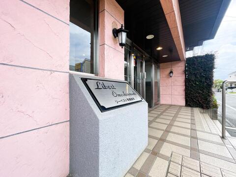 スタイリッシュな館名サインがゲストを迎えるアプローチ。華やかなピンクベージュのスタッコ調外壁に、クラシカルでお洒落なダウンライトが調和し、マンションの品格と暖かみを演出します。