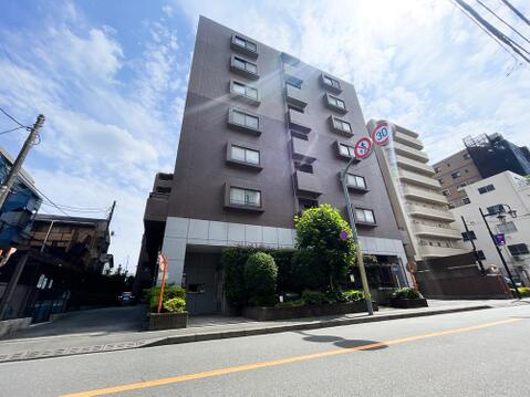 落ち着いたブラウンのタイル貼りと、1階部分のシャープな大理石調デザインが美しいコントラストを描く外観。青空に向かって堂々とそびえ立つシャープなフォルムが、街並みの中でも一際目を引く洗練された佇まいです