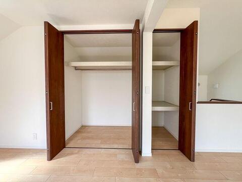 リビング内の大型収納を開けた状態です。左側はアウターや衣服を掛けられるハンガーパイプ仕様、右側は小物の大きさに合わせて高さを変えられるシステム棚になっています。