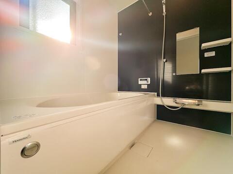 ブラックのアクセントパネルが印象的なバスルーム。ゆったりとした浴槽に加え、シャワーやミラー、収納棚などを備えています。窓も設けられており、落ち着いた雰囲気の中で一日の疲れを癒やせる空間です。