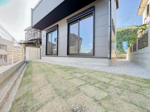 建物に面して設けられた庭スペース。芝生部分と砂利敷きの部分があり、屋外での過ごし方に合わせて活用を検討できます。室内の大きな掃き出し窓から庭へと視線がつながり、住まいに広がりを感じられます。