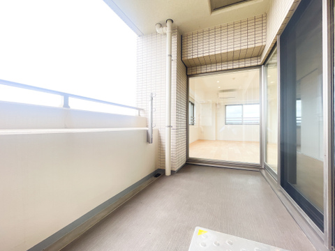 お部屋のフローリングからフラットに視線が抜ける、ゆとりあるワイドバルコニー。上部にしっかりとした庇があり、手すり壁が光を優しく通すため、プライバシーを守りつつ心地よい風を感じられる快適な空間です。