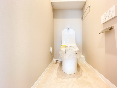 やわらかな色調の内装でまとめられた、落ち着きのあるトイレ空間。トイレットペーパーのストックや掃除用品をすっきりと隠して収納できる、便利なアッパーキャビネットを完備しています。
