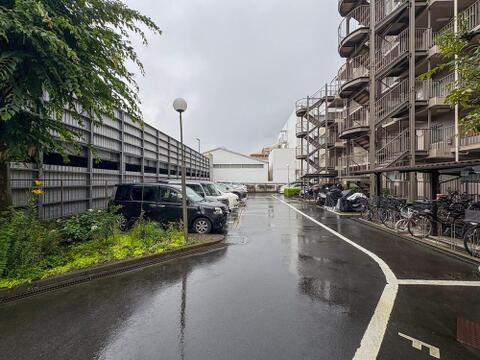雨上がりのしっとりとした路面が印象的な駐車場です。お車での外出もスムーズで、お子様との送迎や買い物にも便利。螺旋階段が特徴的な建物が隣接し、暮らしを快適にサポートします。