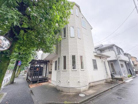 白い外壁と個性的な窓が目を引く、角地の邸宅です。豊かな緑の街路樹が彩る落ち着いた住環境で、お子様との散歩も楽しめます。