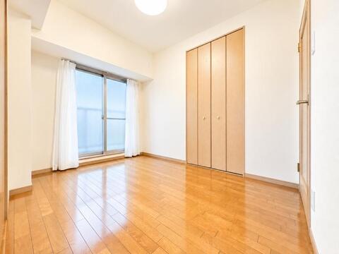 バルコニーに面した大きな窓から優しい自然光が注ぐ洋室。折れ戸式の壁面クローゼットを完備しており、衣類や小物をすっきり収納してお部屋を広々と心地よくお使いいただけます。