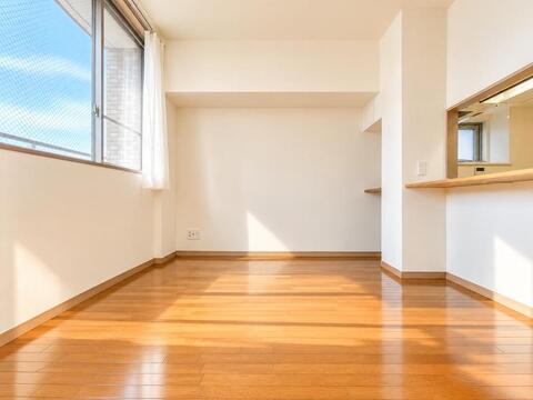 ワイドな窓からあたたかな陽光が差し込む開放的なリビング。木目のフローリングが心地よい温もりを演出し、キッチンカウンターと一体となった使い勝手の良い居住スペースとなっています。