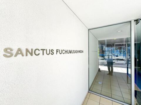 「SANCTUS FUCHUMUSASHINODAI」のロゴが輝く、洗練されたエントランス。AEDも完備され、ご家族の安心を支える共用空間です。