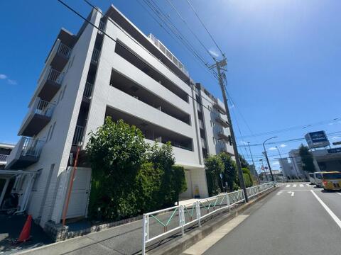 青空に映える、洗練された外観のマンション。陽光あふれるバルコニーで、家族の笑顔が弾む快適な暮らしが待っています。