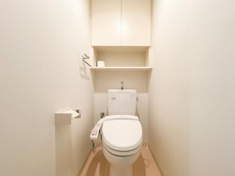 温水洗浄便座完備の清潔なトイレ。トイレットペーパー等のストックに重宝する吊戸棚・棚板付き。