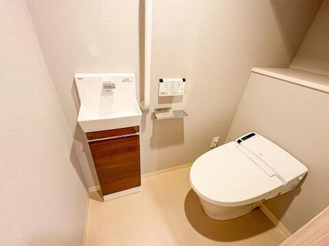 LIXIL製ウォシュレット完備の清潔なトイレ空間。手洗いカウンターと手すりも備え、ご家族みんなが安心して使える設計です。