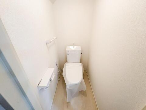 白を基調とした清潔感あふれるトイレ空間。新しい設備と便利な収納棚で、ご家族皆様が快適に使えるプライベートスペースです。