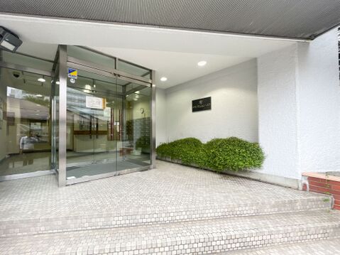 「チサンマンション八王子」。綺麗な植栽とガラス扉が住まう人を爽やかにお出迎えするアプローチ。