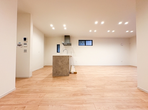 温かみのある木目調フロアとシックなグレーのキッチンカウンターが調和した広々LDKです。ダウンライトが優しく空間を照らし、料理中も家族との会話が弾む開放的でスタイリッシュな居心地の良いリビングです