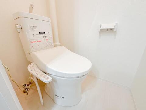 温水洗浄便座を備えたトイレ。白を基調としたシンプルな内装でまとめられており、毎日使用する水まわりをすっきりとした印象に仕上げています。