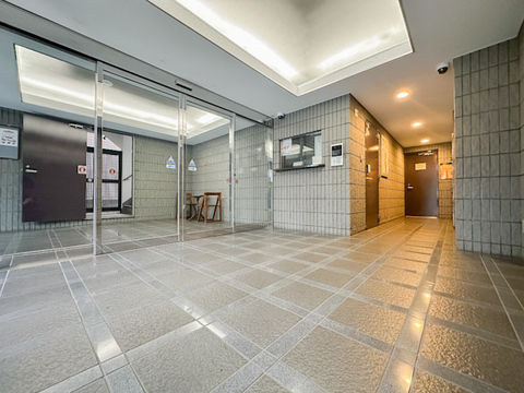 ガラス扉を採用したマンションエントランス。床面はタイルで仕上げられ、建物の外と共用部をつなぐ、すっきりとした印象の空間です。