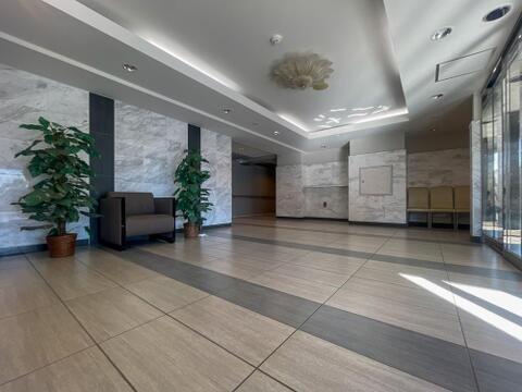 マンションのエントランスホールは、大理石調の壁面や床材が用いられたゆとりのある空間です。来客時の対応やちょっとした休憩にも利用できるソファが配置され、観葉植物が彩りを添えています。