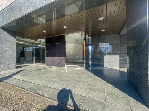 「CENTURY OUME SHINMACHI」の館銘板が掲げられたエントランスです。重厚感のあるダークトーンの外壁と、光を取り込むガラス張りの自動ドアがスタイリッシュな印象を与えます。