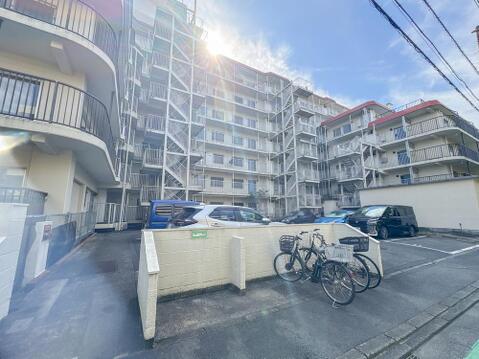 敷地内に設けられた契約者用のバイク置場スペース。区画が分かりやすく整備されており、奥には平坦な駐車場や共用アプローチが広がる利便性と管理体制の行き届いた住環境です。
