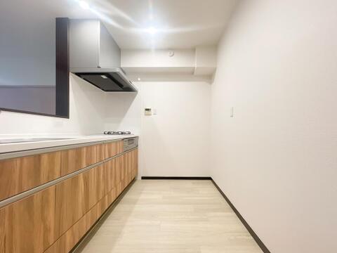 温かみのある木目調の面材を採用したシステムキッチンです。3口ガスコンロが備わっており、複数のお料理を同時に効率よく進めることができます。作業スペースも確保されています