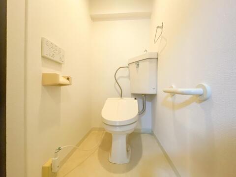 壁面に温水洗浄便座の操作パネルが設置されており、すっきりとした空間でお手入れもしやすいトイレです。立ち座りの動作をサポートする手すりが備え付けられており、ご家族皆様が利用しやすい造りです。