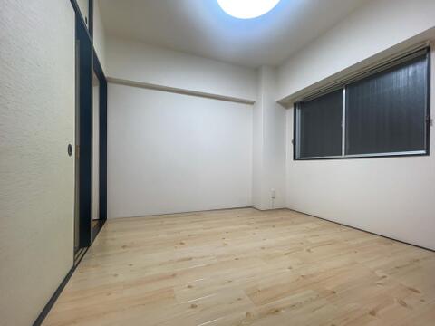 明るい色合いの木目調の床材が敷かれたお部屋です。引き戸にはふすまのような和の雰囲気を感じさせるデザインが取り入れられています。窓から自然光を取り込むことができるシンプルな空間です。