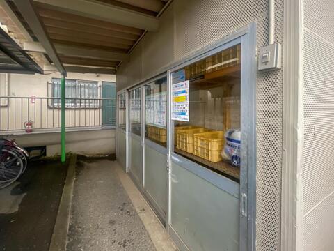 敷地内に設けられた専用のゴミ置き場です。引き戸で仕切られた屋内のスペースに分別用のカゴが並んでおり、日々の管理体制の良さがうかがえます。カラスや猫などによるゴミの散乱を防ぐ造りです。
