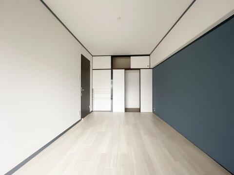 壁の一面に落ち着いた青系のアクセントクロスが施されたお部屋です。引き戸タイプの収納に加えて、上部にも収納スペースが設けられているため、荷物をすっきりと整理することができます。