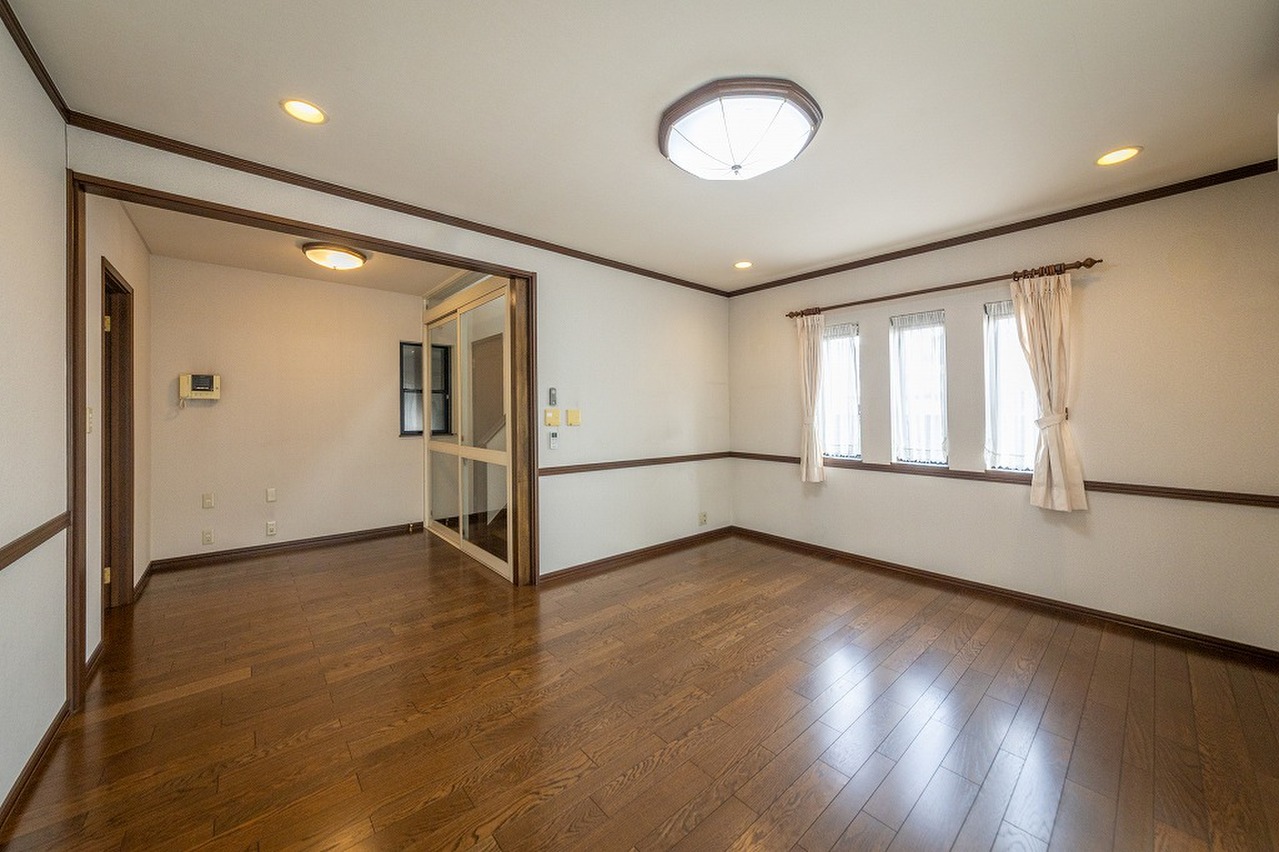 【1階書斎】2階のLDKへ繋がる階段があり、生活動線に配慮された設計です。2面に採光が確保され、窓から明るい陽光が差し込みます。様々な家具と調和しやすいシンプルな内装です。