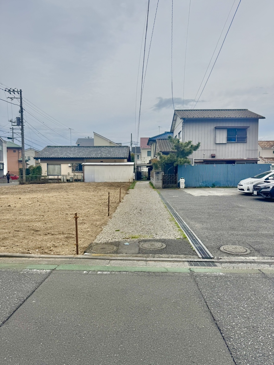 【前面道路含む現地写真】分譲地の南西側は、現況通路と駐車場です。真ん中の区画ながら、北東・南西側の二方からの陽光を採り込むこともできそうです。