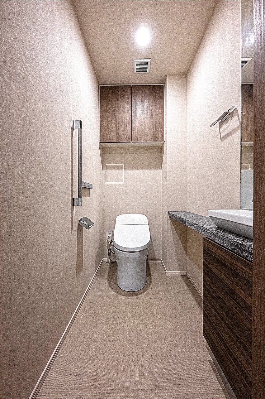 落ち着いた色合いでまとめられたトイレ。温水洗浄便座付きで、寒い時期でも温かな便座で快適に使うことができます。独立した手洗い器があり、いつでも清潔に使える空間です。