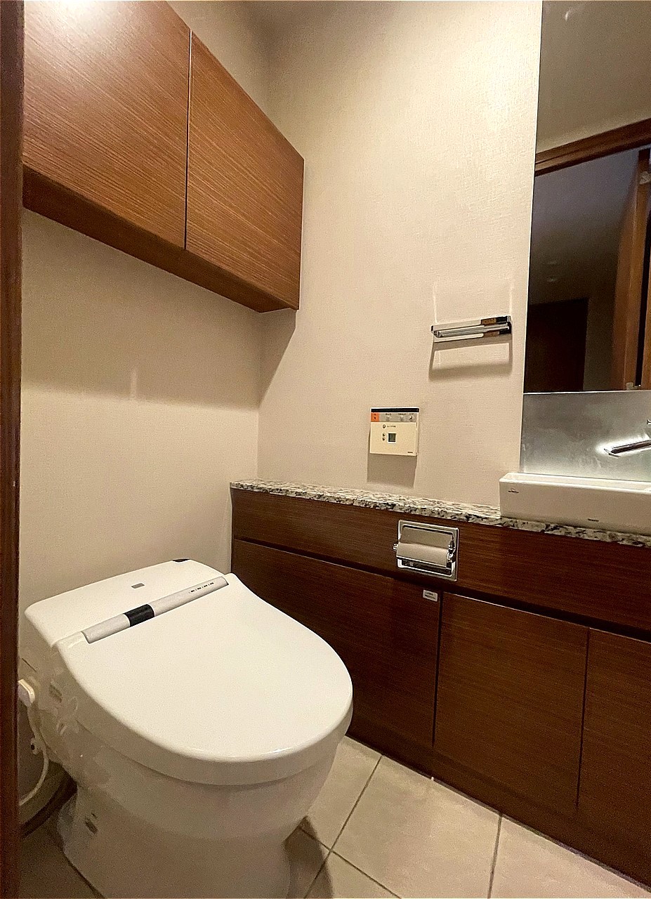 温水洗浄便座付きのトイレです。寒い時期でも温かな便座で快適に使うことができます。上部には、トイレットペーパーなどを収納できる吊り戸棚があります。