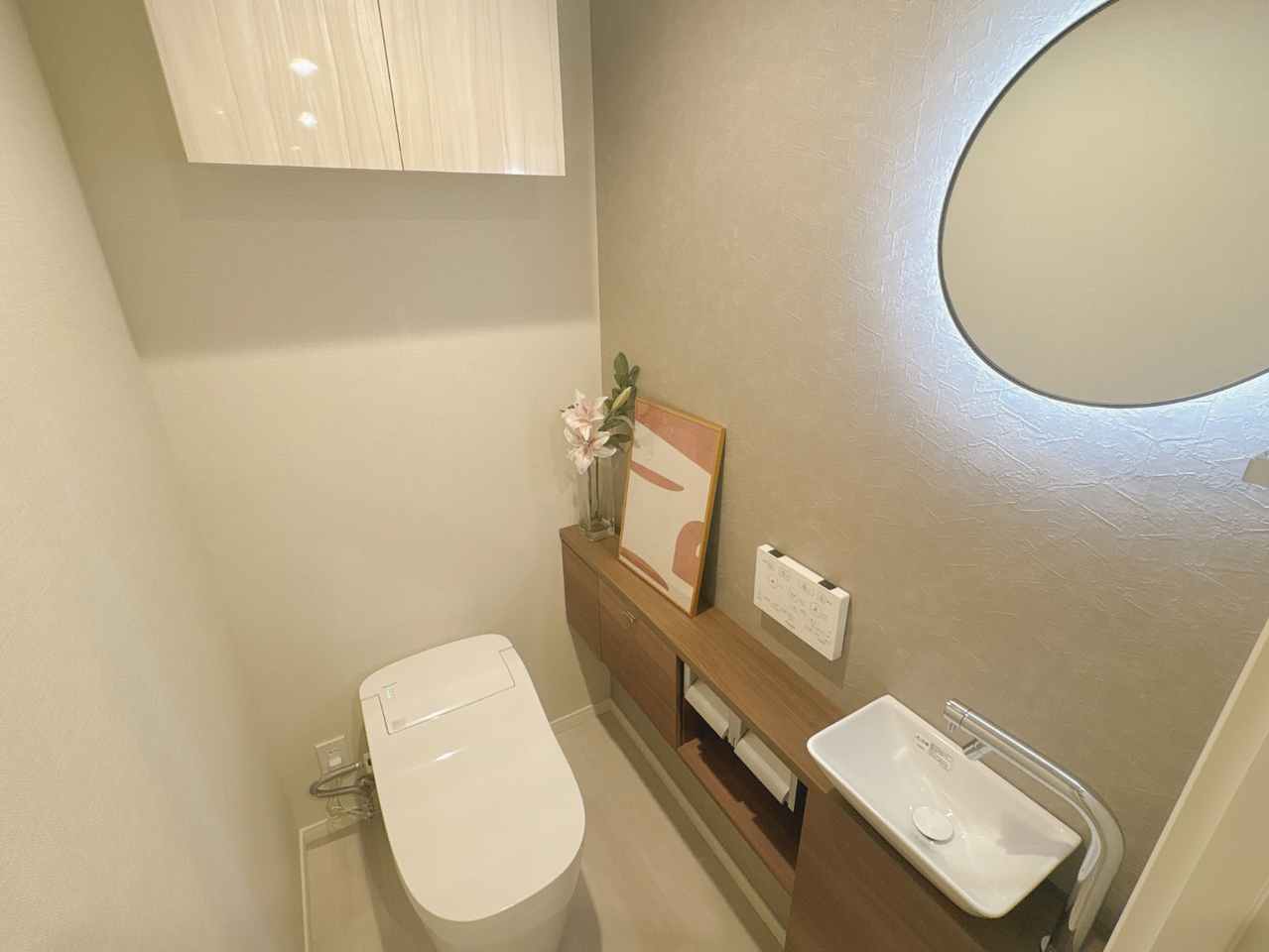 丸型のミラーが印象的なトイレ空間。温水洗浄便座付きで、毎日快適に利用できます。リモコンが壁に設置され、操作しやすい仕様です。