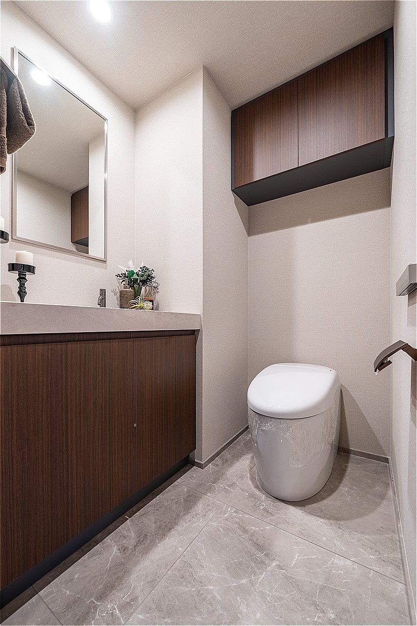 清潔に利用できる温水洗浄機能付きトイレです。上部と手洗い下に収納スペースがあり、トイレットペーパーや掃除用品を収納できます。