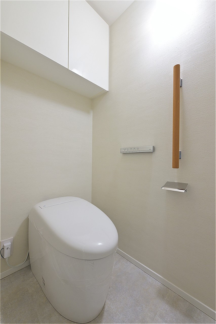 スタイリッシュな印象のトイレです。背面に吊り戸棚があり、トイレットペーパーのストックや掃除用具の収納に便利。1年中快適に使用できる温水洗浄便座付きです。
