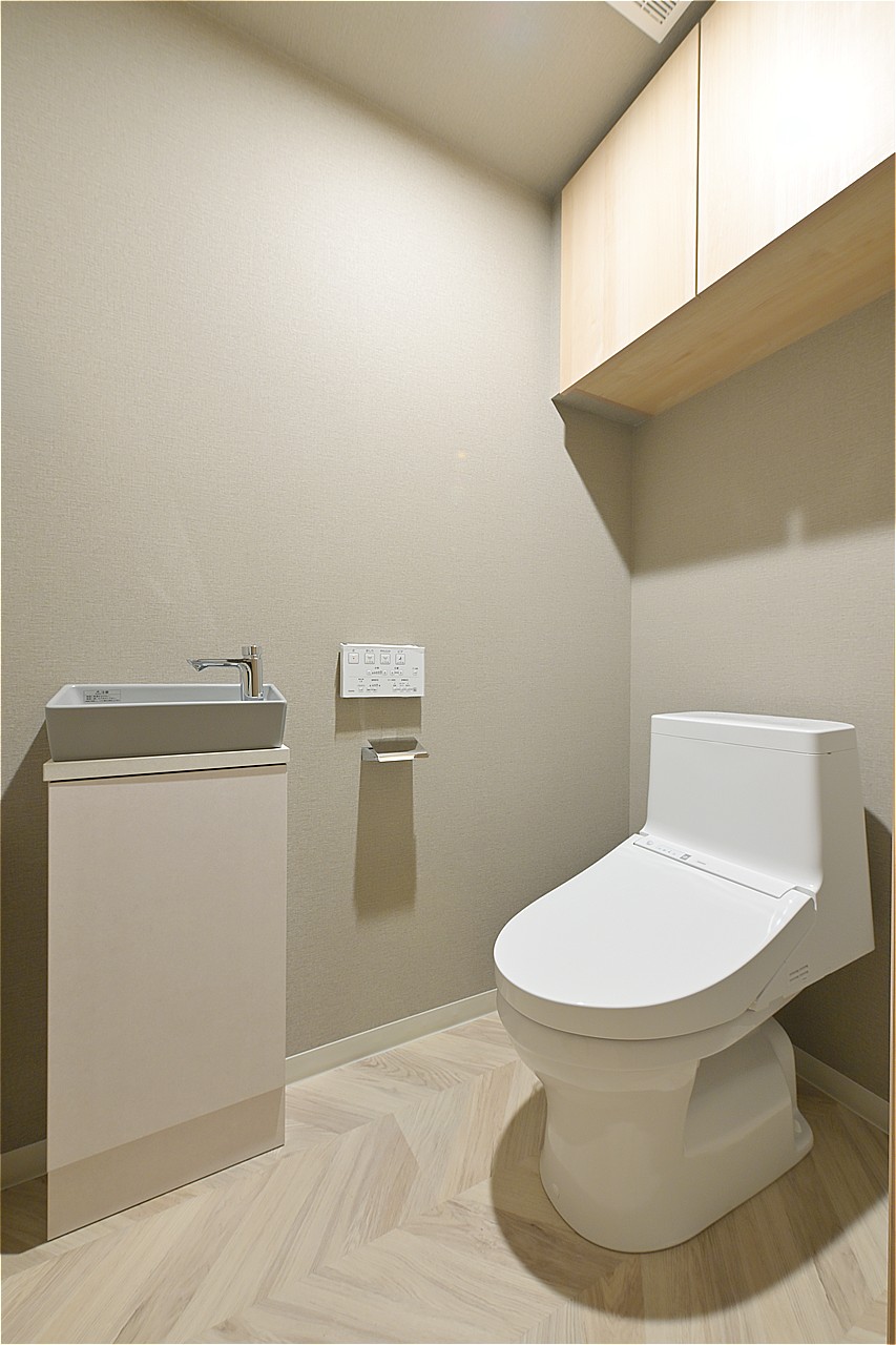 トイレには手洗いカウンターを設置。使用後すぐに手が洗え衛生的です。背面の吊戸棚にトイレットペーパーや掃除用品などを収納できます。