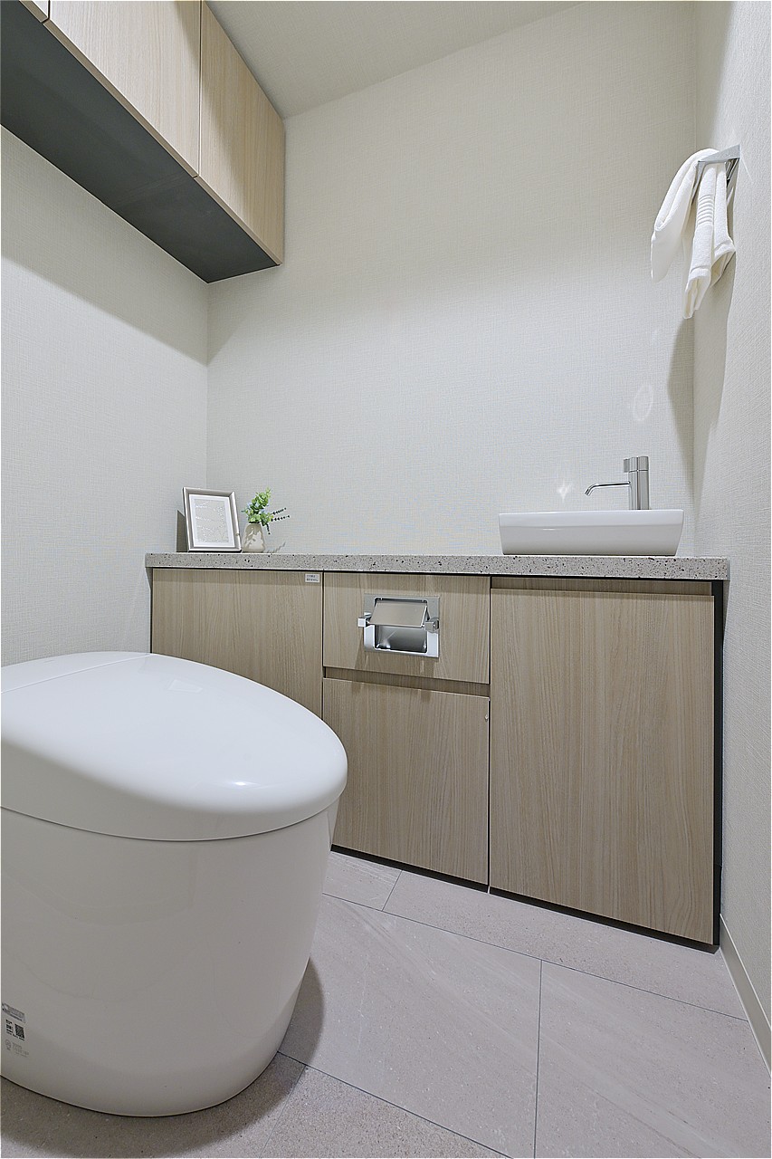 清潔に利用できる温水洗浄機能付きトイレです。上部と手洗い下に収納棚を設けています。トイレットペーパーや掃除用品をきれいに収納することができます。