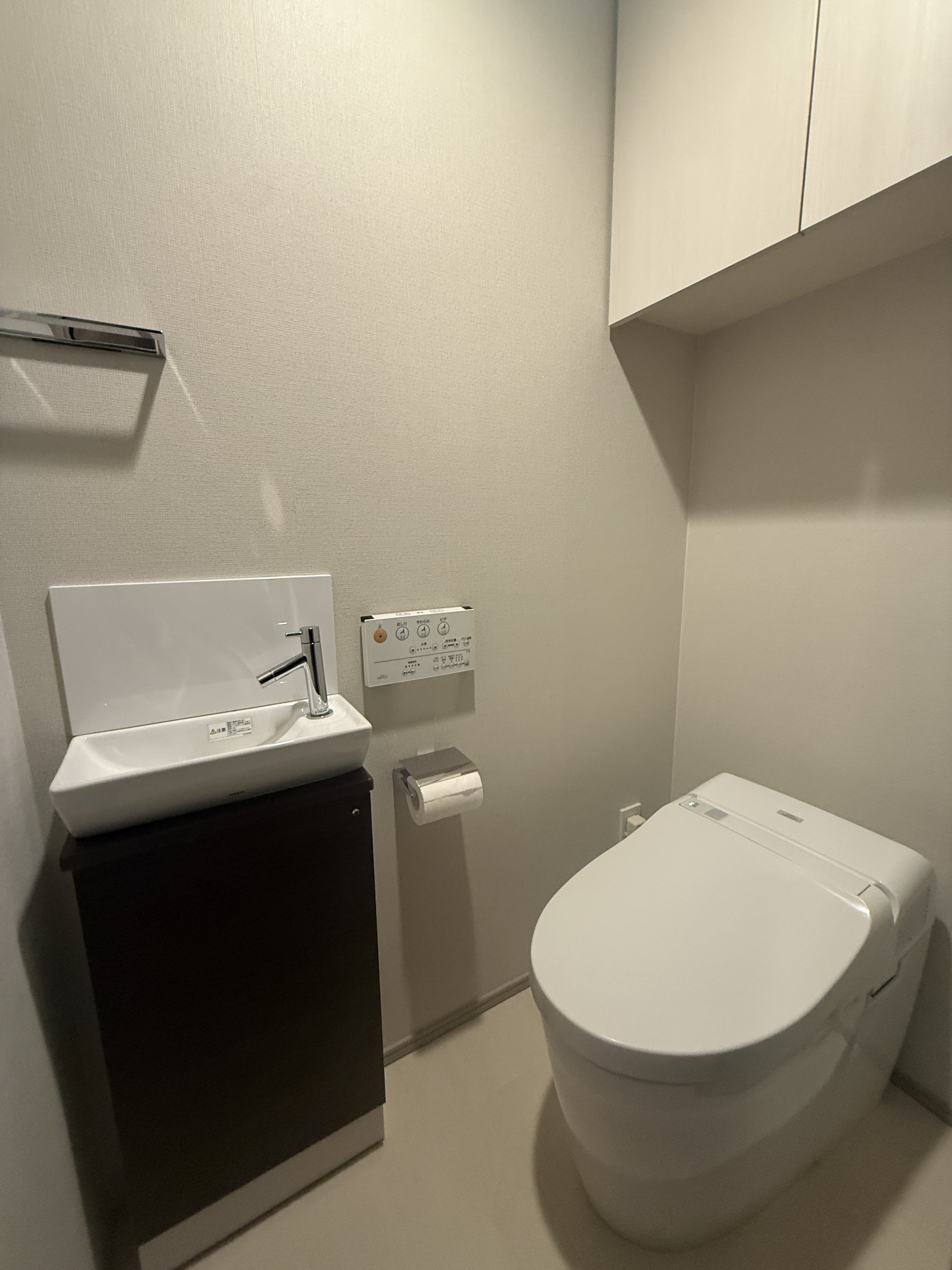 【トイレ】毎日快適にお使いいただける、温水洗浄便座付きです。手洗いがしやすい独立型の手洗い器や、トイレットペーパーなどの収納にも重宝する吊戸棚が設けられています。