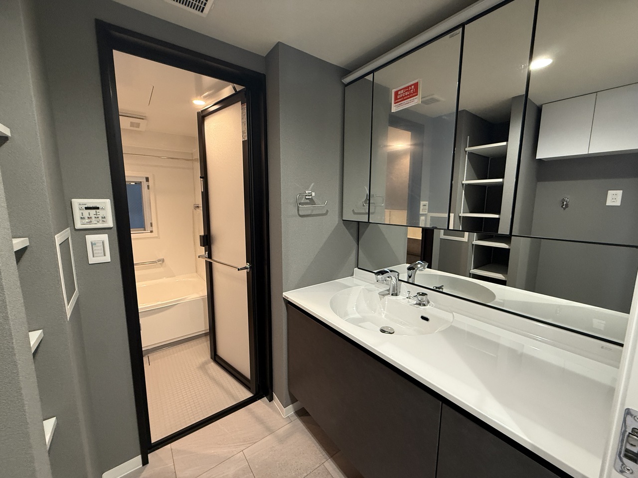 【洗面室】ミドルミラー付きのゆとりのある洗面化粧台が備わっています。鏡の裏やボウル下には収納スペースがあり、ドライヤーや化粧品類が片付きます。背面には可動棚あり。