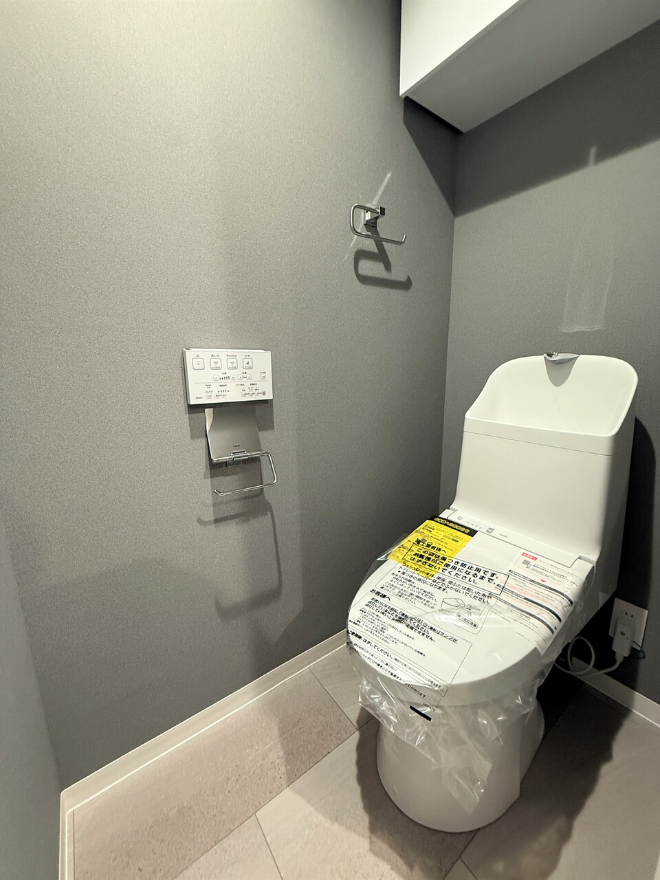 【トイレ】毎日清潔にご使用いただける温水洗浄便座が設置されています。壁にリモコンが備え付けられているので操作がしやすいです。トイレットペーパーなどの収納に便利な吊戸棚付き。