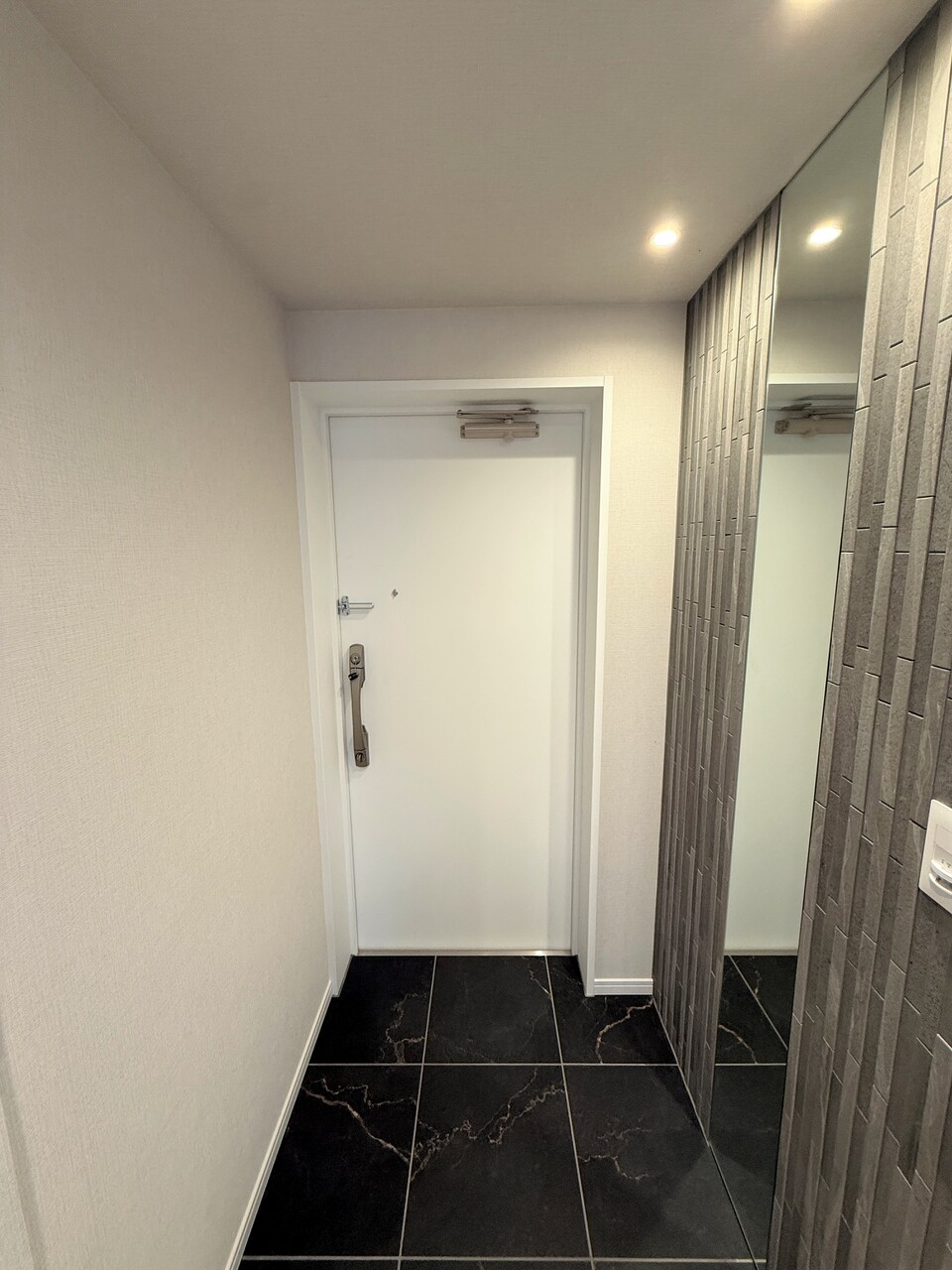 【玄関】黒の石目調タイルでシックな雰囲気が演出された玄関。お出掛け前の身だしなみチェックに便利な姿見が備え付けられています。