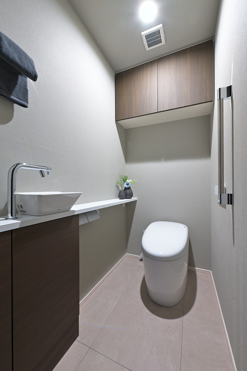 【トイレ】温水洗浄便座付きのトイレです。手洗いがしやすく、見た目がすっきりとした手洗いカウンターを採用しています。背面に収納棚があり、トイレットペーパー等を仕舞えます。