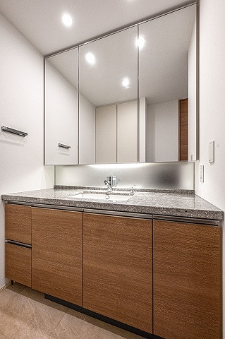 【洗面化粧台】3面鏡とミドルミラーが備わった洗面化粧台。並んで作業が行えるゆとりある幅です。鏡裏や手洗いボウル下部に、洗面用品やタオル・ストック類を保管できます。