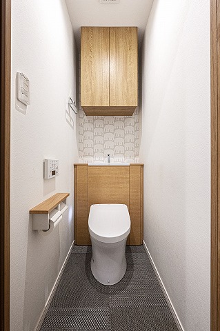 【トイレ】清潔に利用できる温水洗浄機能付きトイレです。上部には収納棚が設置されており、トイレットペーパーや掃除用品を収納することができます。